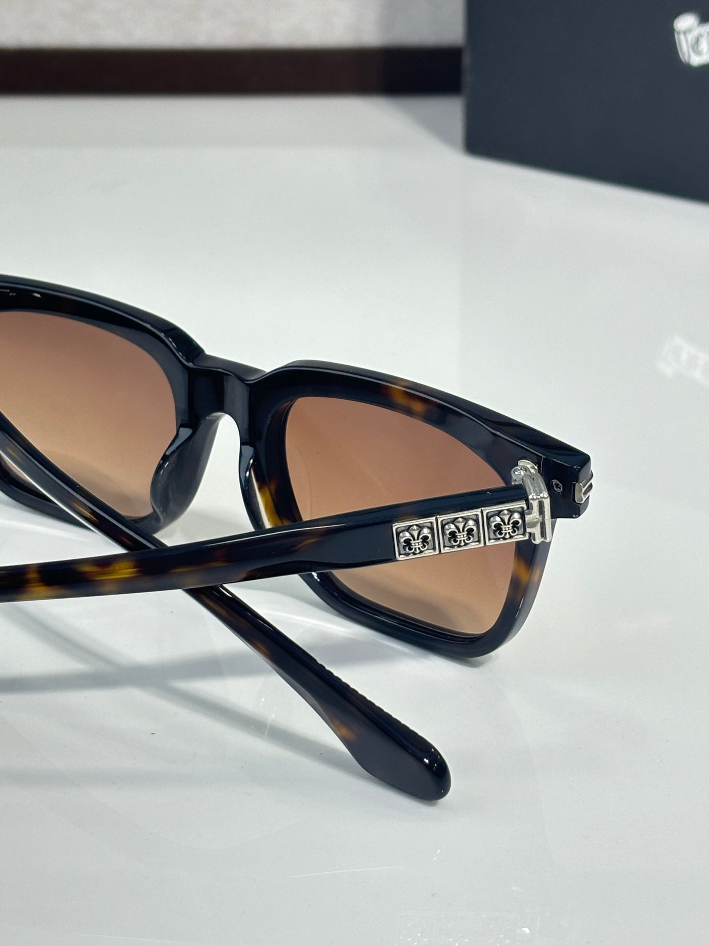 Chrome glasses close-up with dark tortoise frame, amber lenses, engraved temple bar