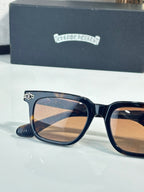 Chrome glasses with dark blue frame, amber lenses, gold emblem on temple