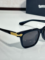 Chrome glasses with black frame, dark lenses, gold medallion detail on bridge