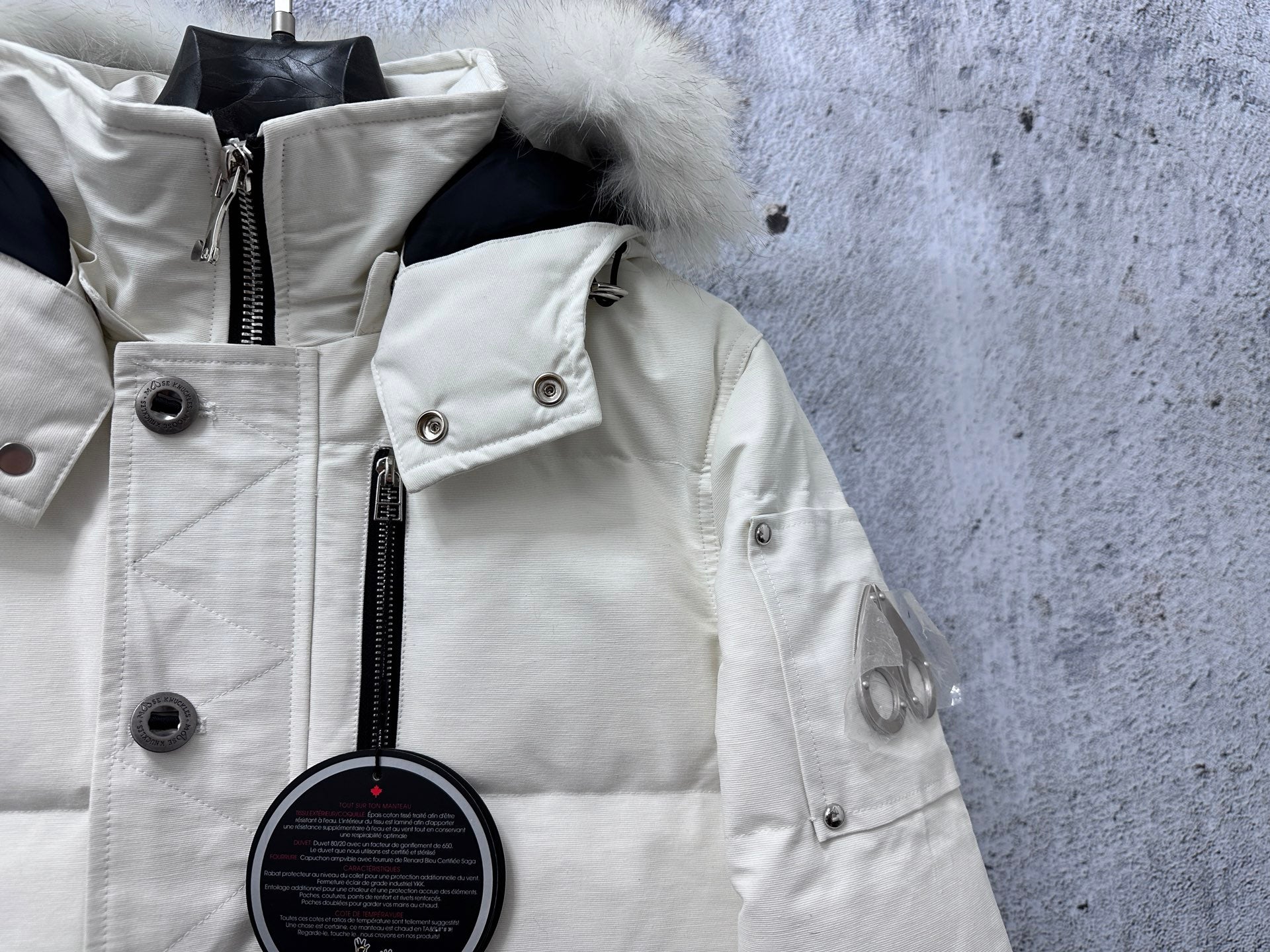 White puffer jacket close-up with hood trim, snap buttons, and zipper placket