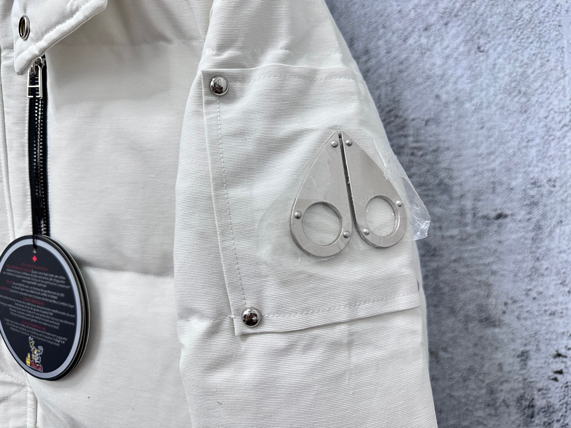 White puffer jacket side close-up with utility pocket and snap button tab
