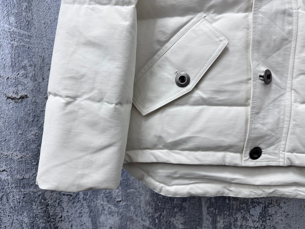 White puffer jacket hem and sleeve with snap buttons and stitched panels
