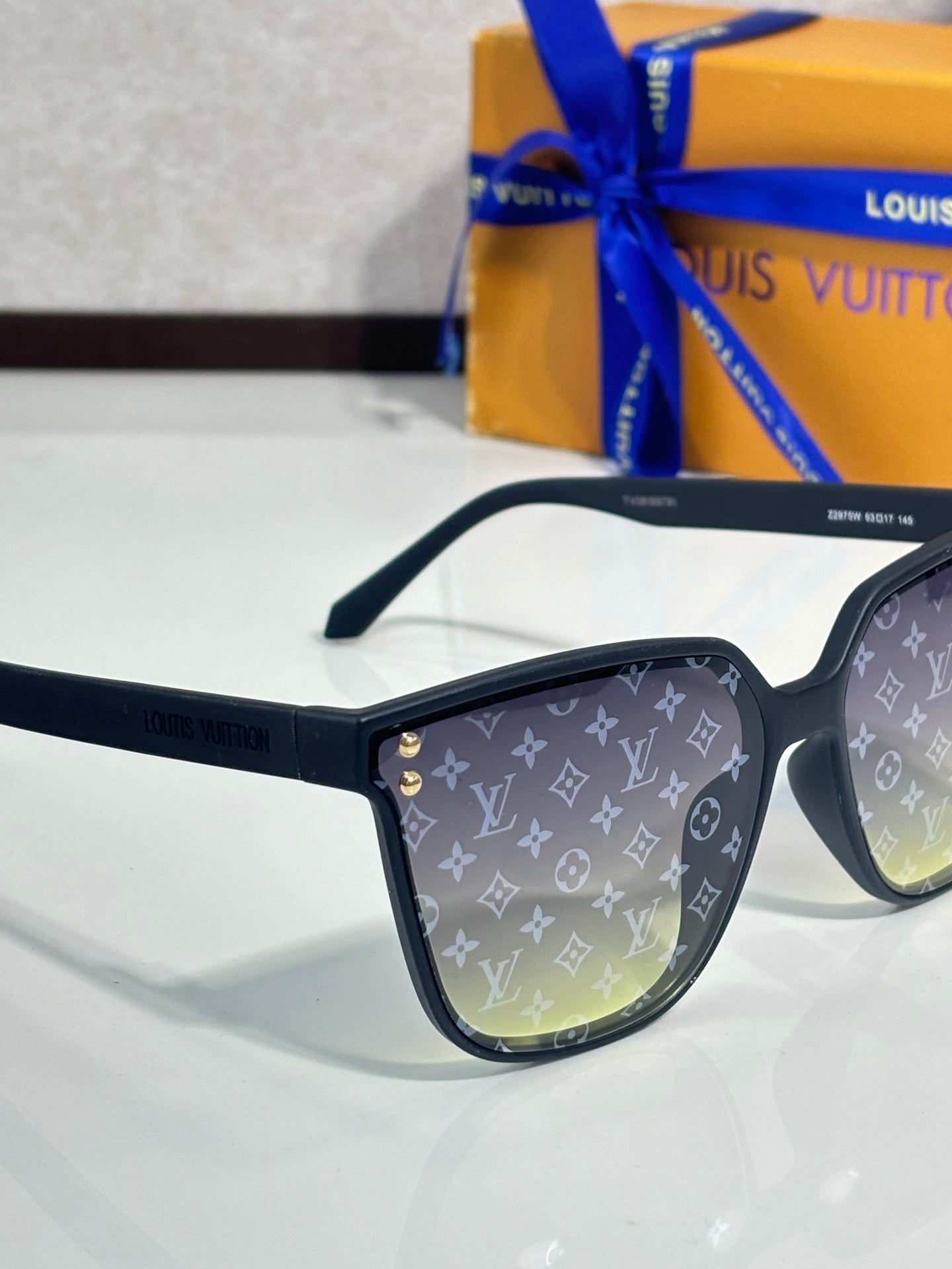 Louis Vuitton sunglasses close-up, black frames, LV monogram on lens