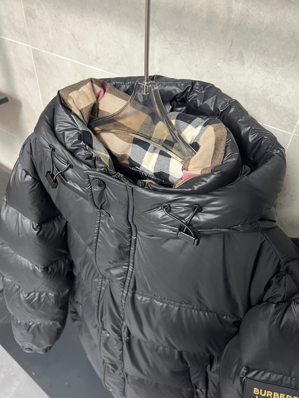 Dark puffer jacket with plaid inner hood and front zipper, quilted baffles