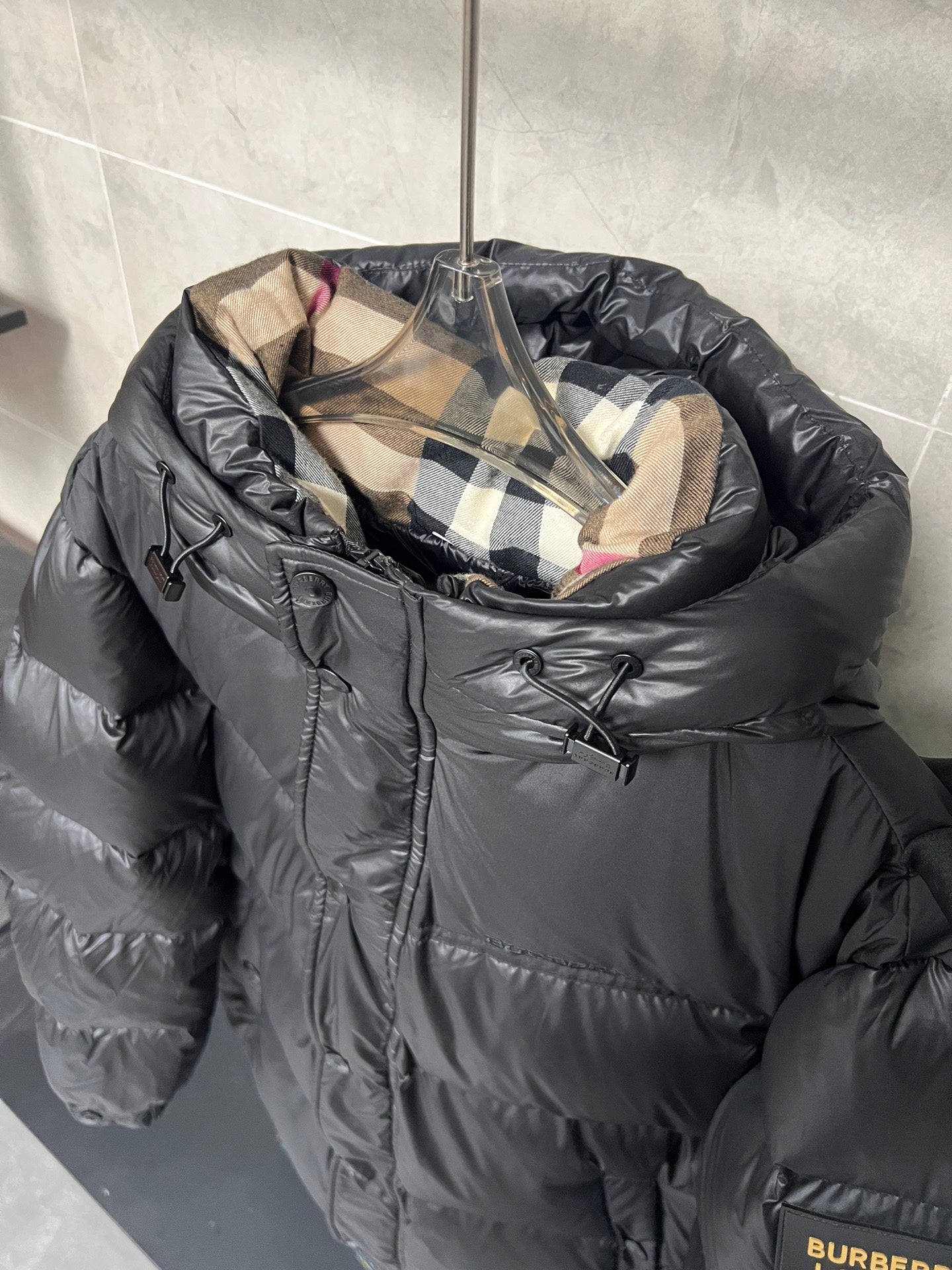 Dark puffer jacket with plaid inner hood and front zipper, quilted baffles