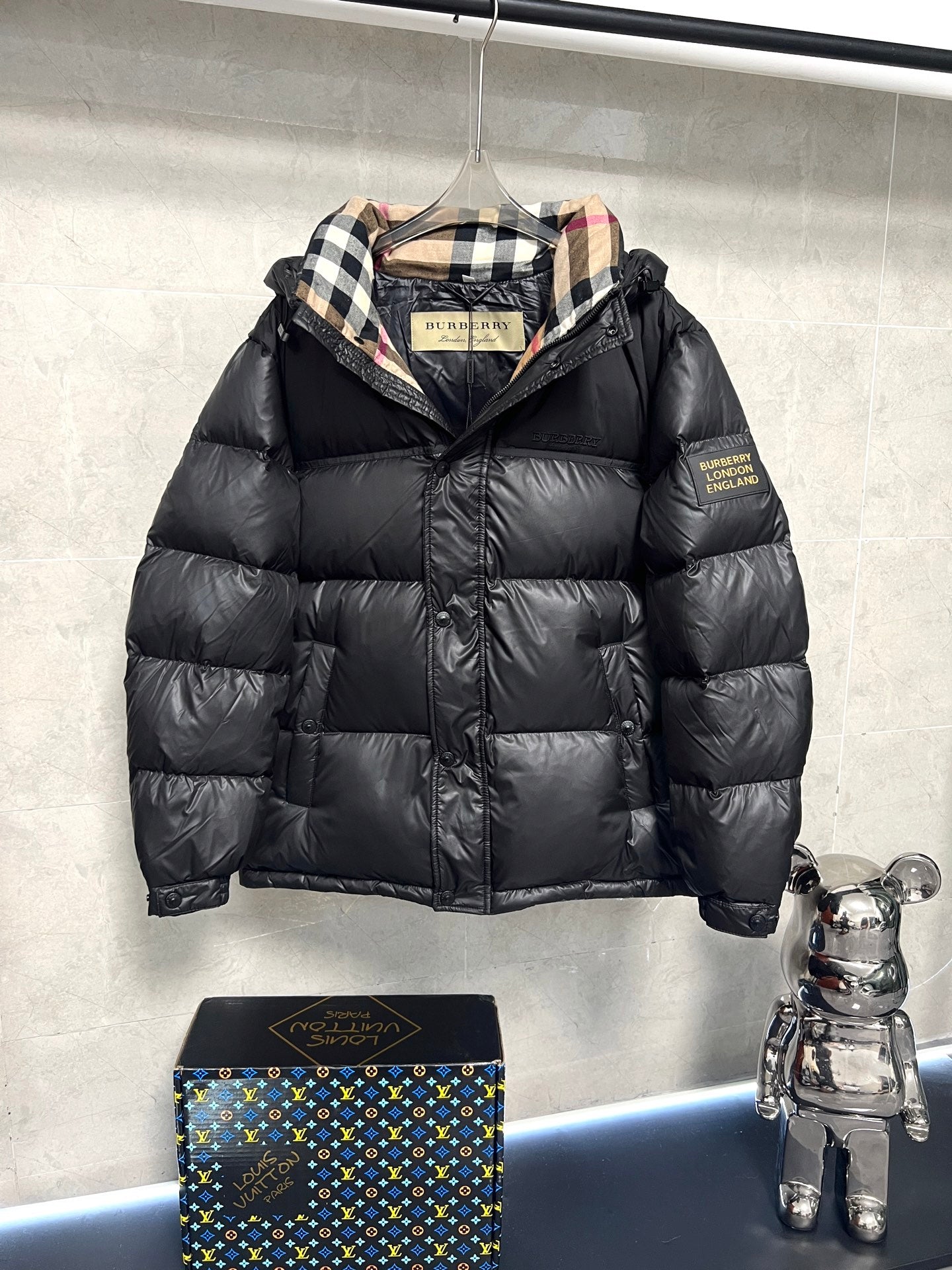 Black puffer jacket with plaid-lined hood and front zipper, quilted design