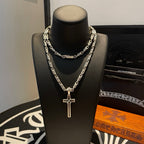 Layered cross pendant necklaces with silver-tone chains on a black display bust