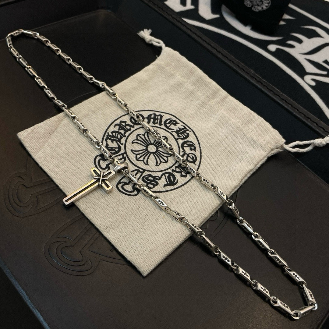 Cross pendant necklace draped over a light fabric pouch with ornate logo