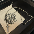 Cross pendant necklace and silver-tone chain on a light fabric pouch