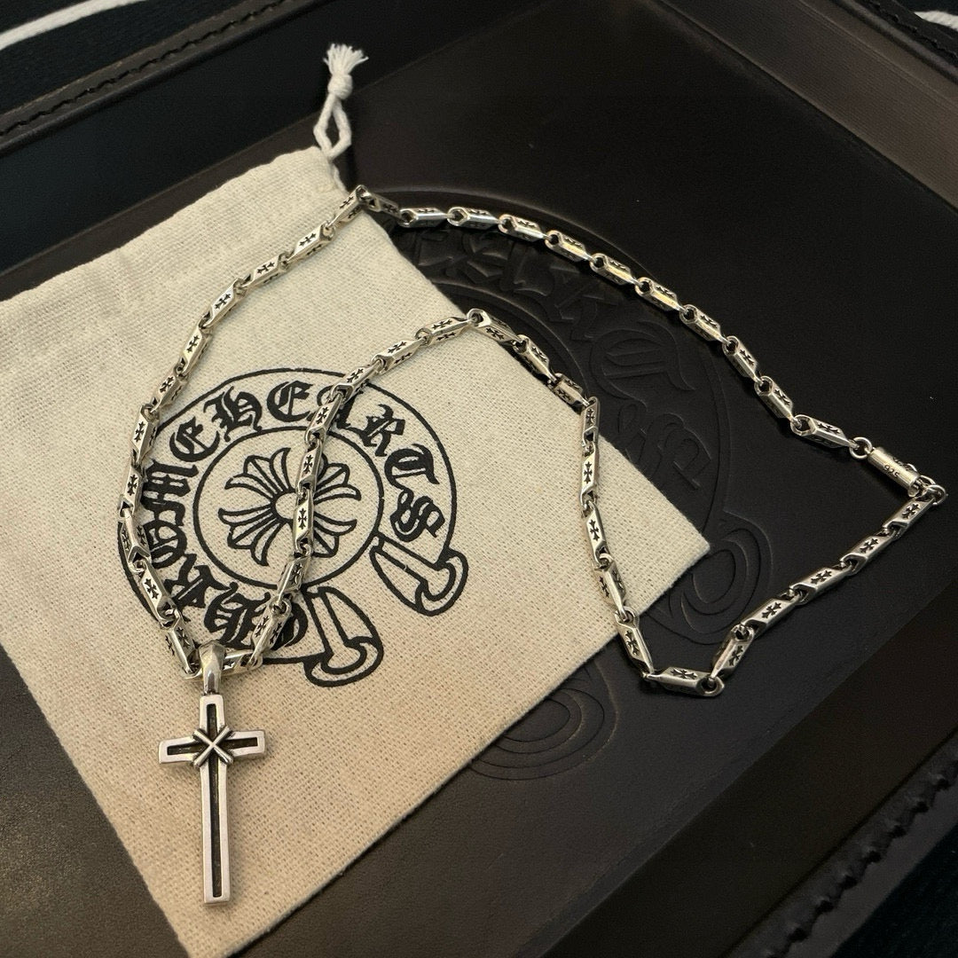 Cross pendant necklace and silver-tone chain on a light fabric pouch