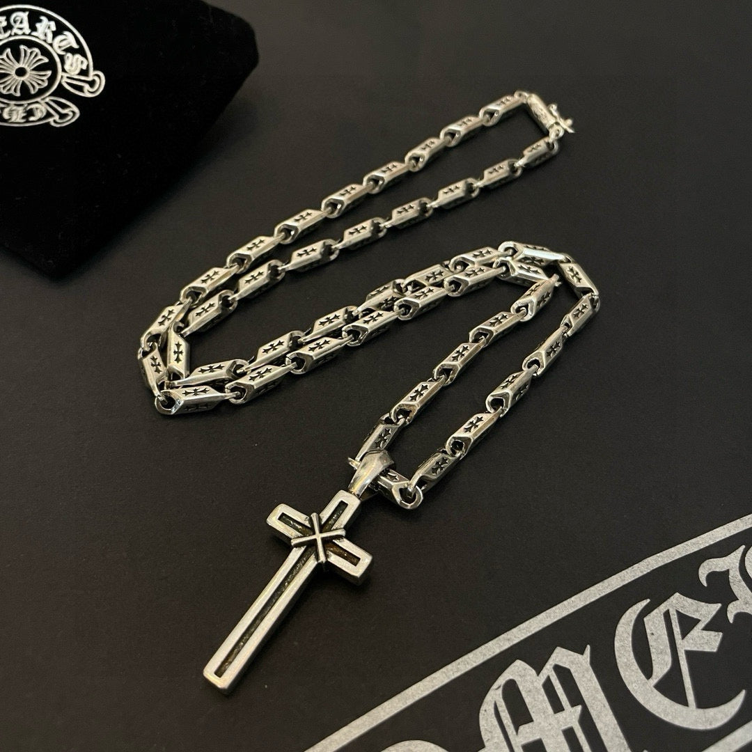 Two silver-tone chain necklaces with cross pendants on a dark background