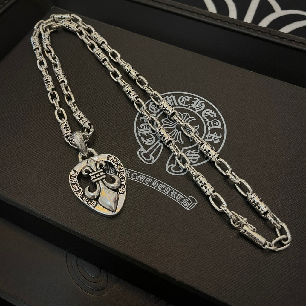 Silver chain necklace with heart crest pendant, laid on a black jewelry box
