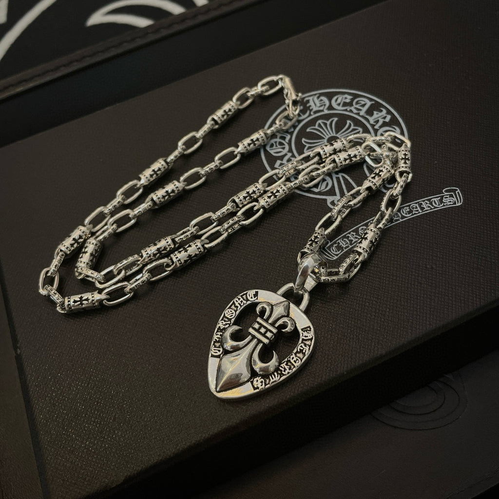 Silver chain necklace set with heart crest pendant, on a dark gift box