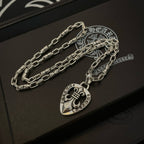 Silver chain necklace set with heart crest pendant, on a dark gift box