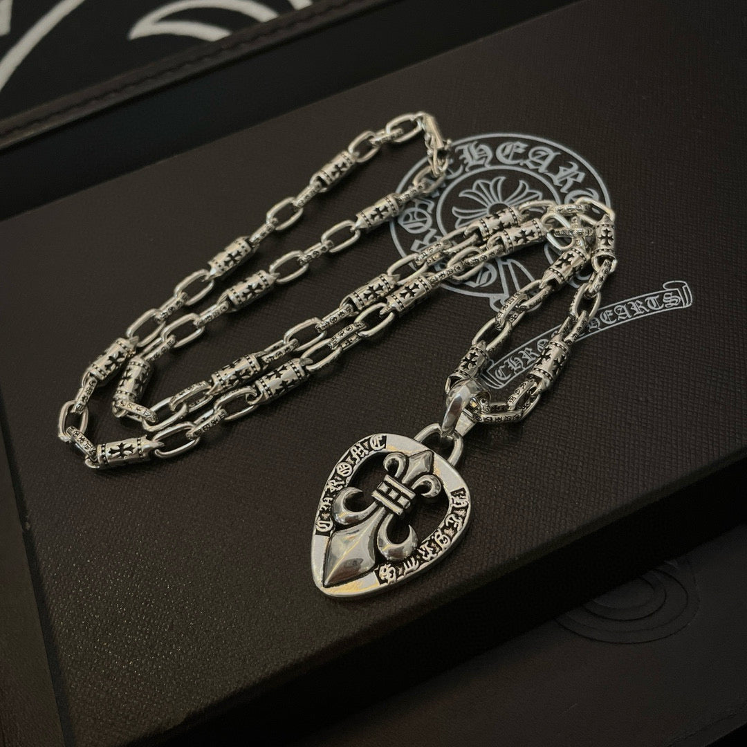 Silver chain necklace set with heart crest pendant, on a dark gift box