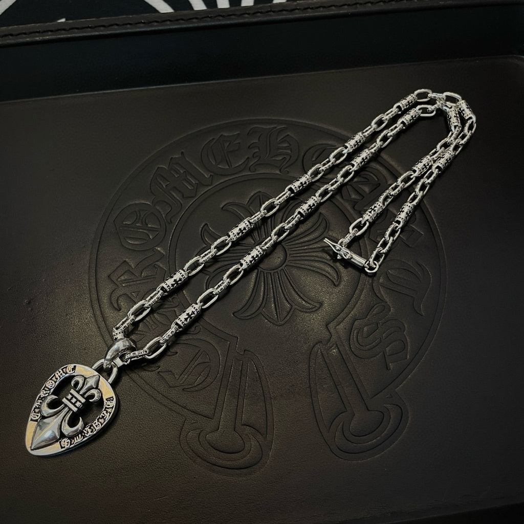 Silver heart pendant necklace with chunky link chain, on a dark leather-like surface