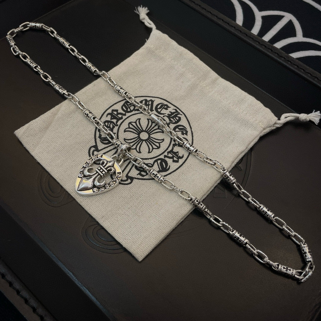Silver heart crest pendant necklace with chain, in a light fabric pouch
