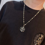 Silver-toned oval pendant necklace on long chain worn on dark T-shirt