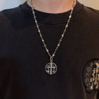 Silver-toned necklace with oval pendant and charm-link chain worn on black shirt