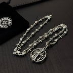 Silver-toned charm necklace with circular pendant and cross-and-flower link details