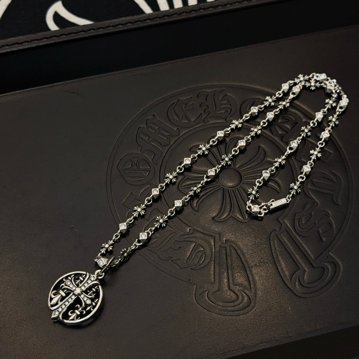 Silver-toned oval pendant necklace with charm-link chain and small floral accents