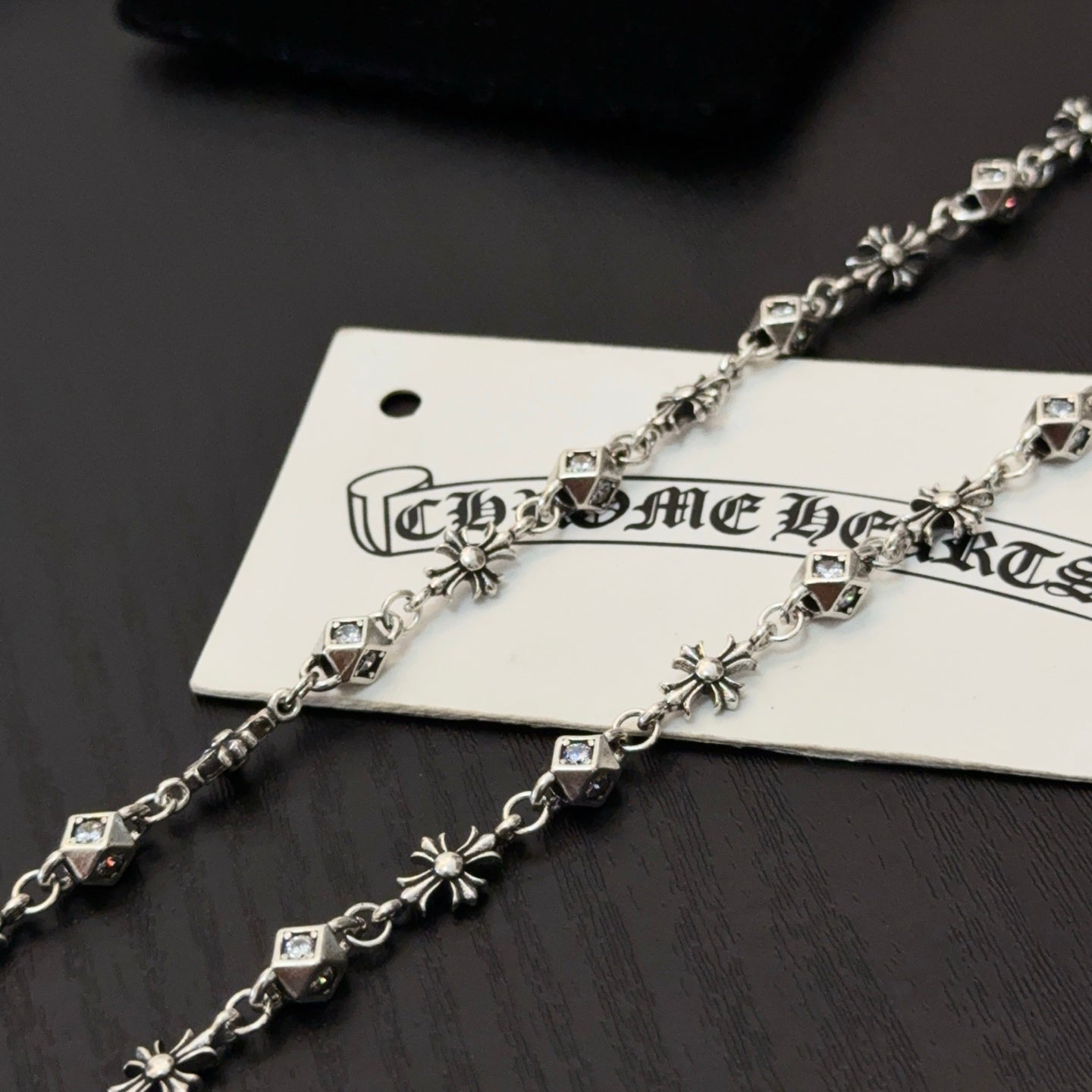 Silver-toned cross pendant necklace with square link accents on hanging tag