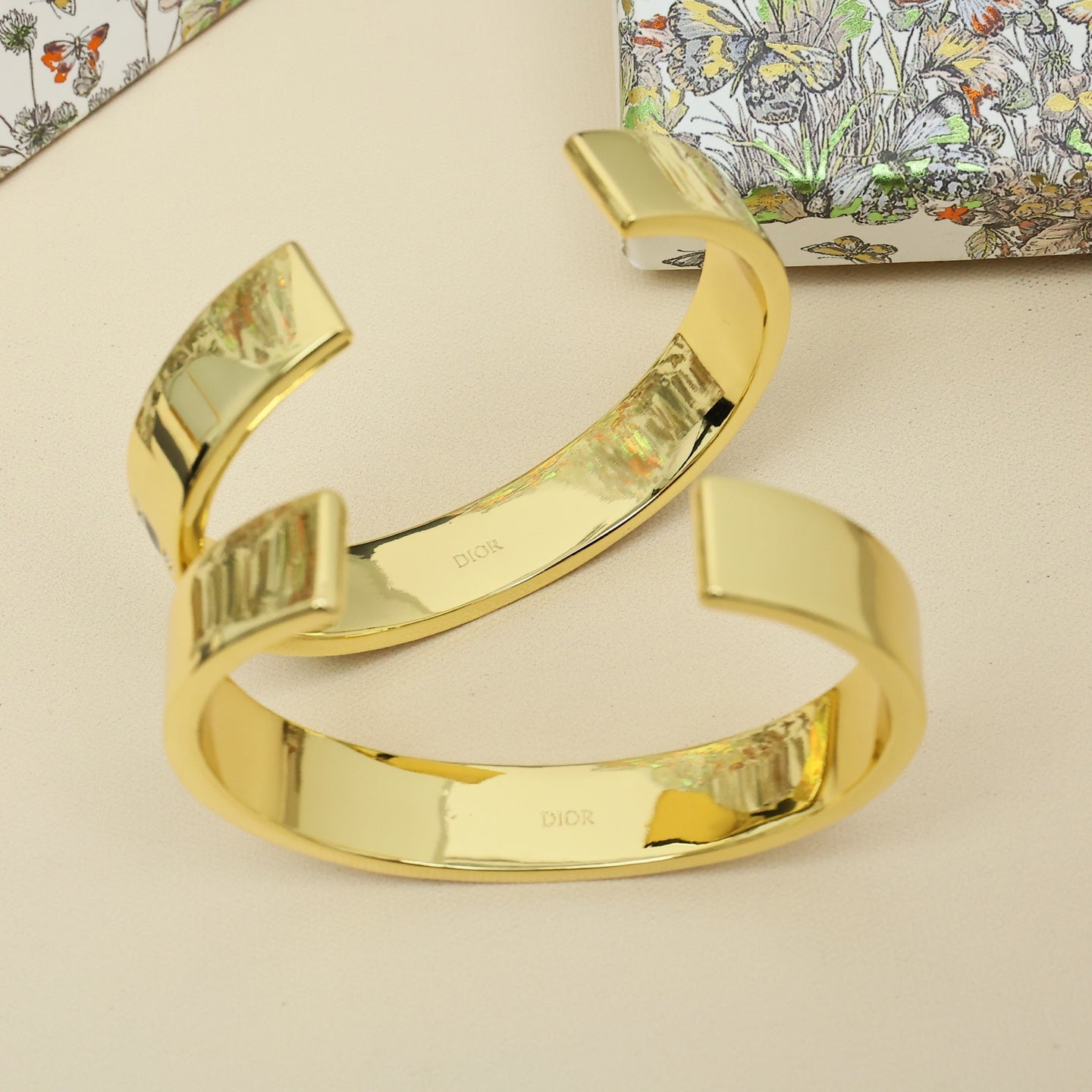 Stacked gold-tone cuff bracelets with engraved details and polished finish