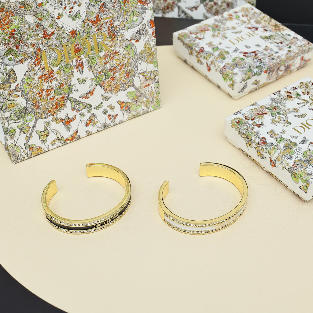 Pair of gold-tone cuff bracelets with rhinestone pavé and black enamel center stripe