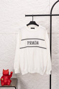 White long-sleeve crewneck sweater with PRADA logo and black striped band across chest