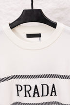 White long-sleeve crewneck sweater with PRADA logo and black striped band