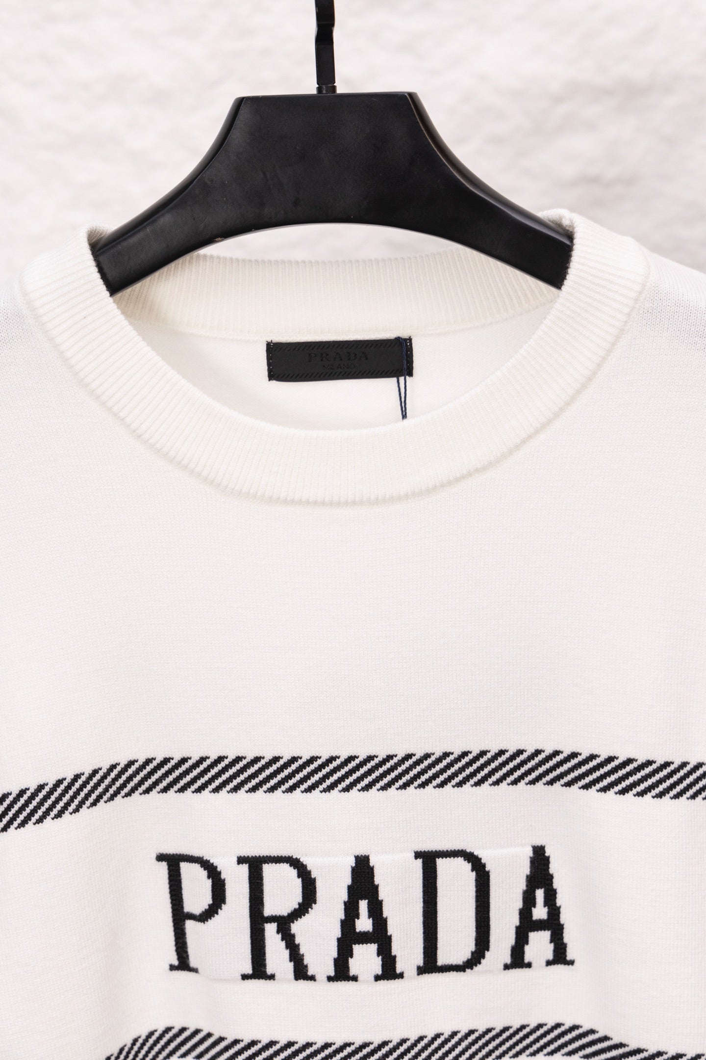 White long-sleeve crewneck sweater with PRADA logo and black striped band