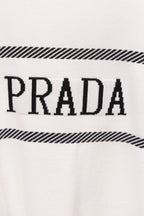 Close-up of white sweater with PRADA lettering and black striped detail