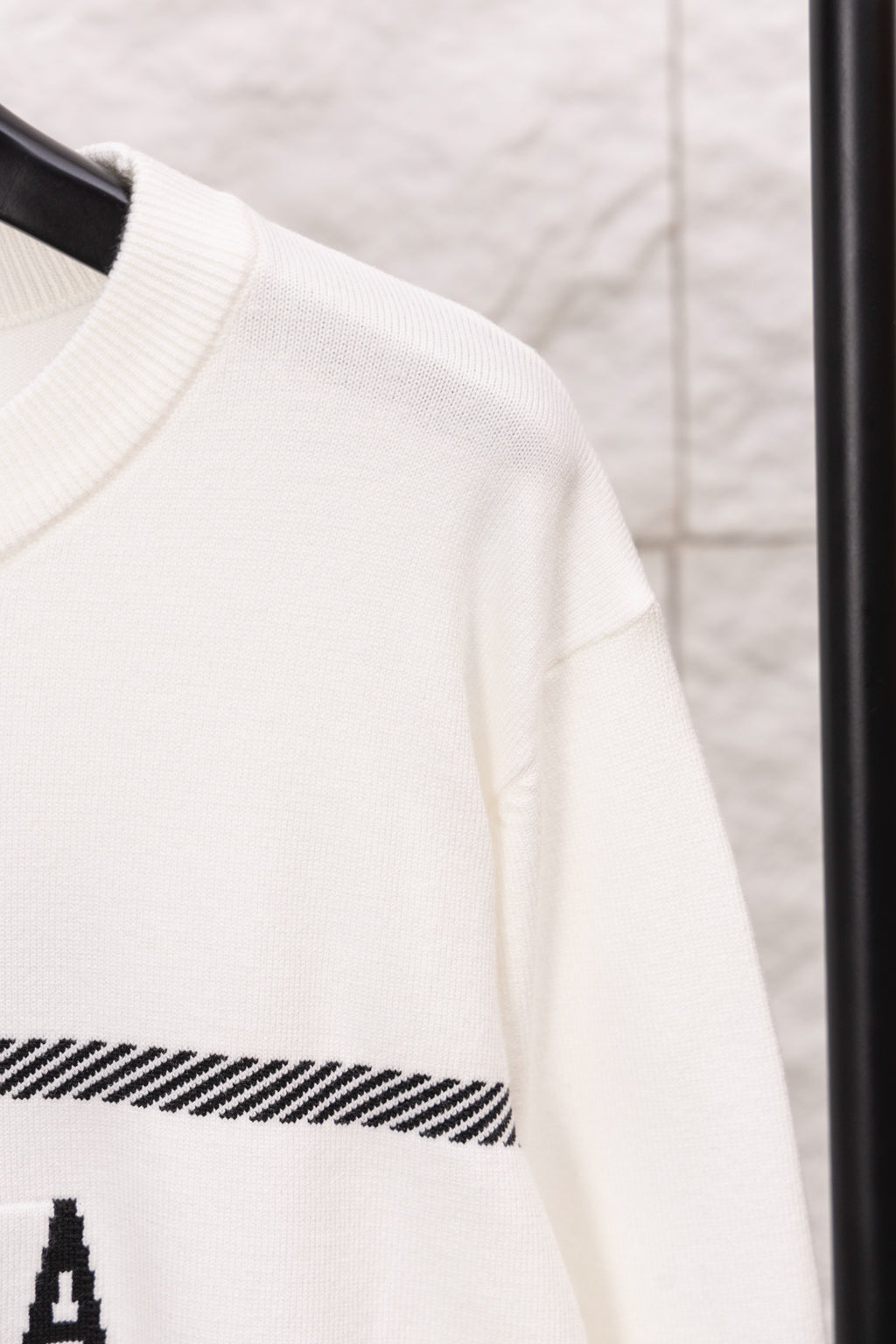 White sweater sleeve with ribbed cuff and black striped band