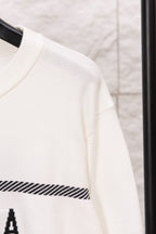 White sweater sleeve with ribbed cuff and black striped band