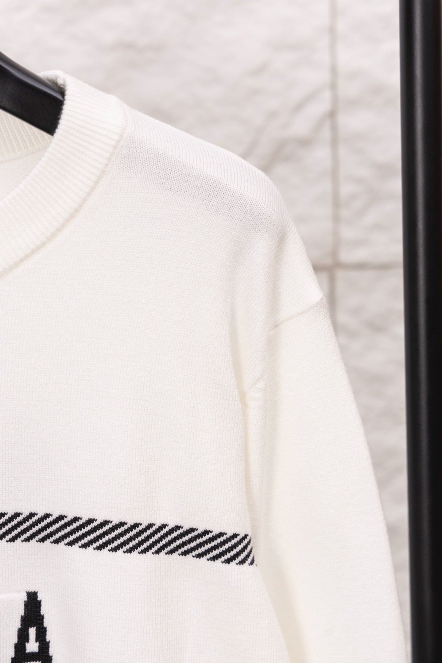 White sweater sleeve with ribbed cuff and black striped band