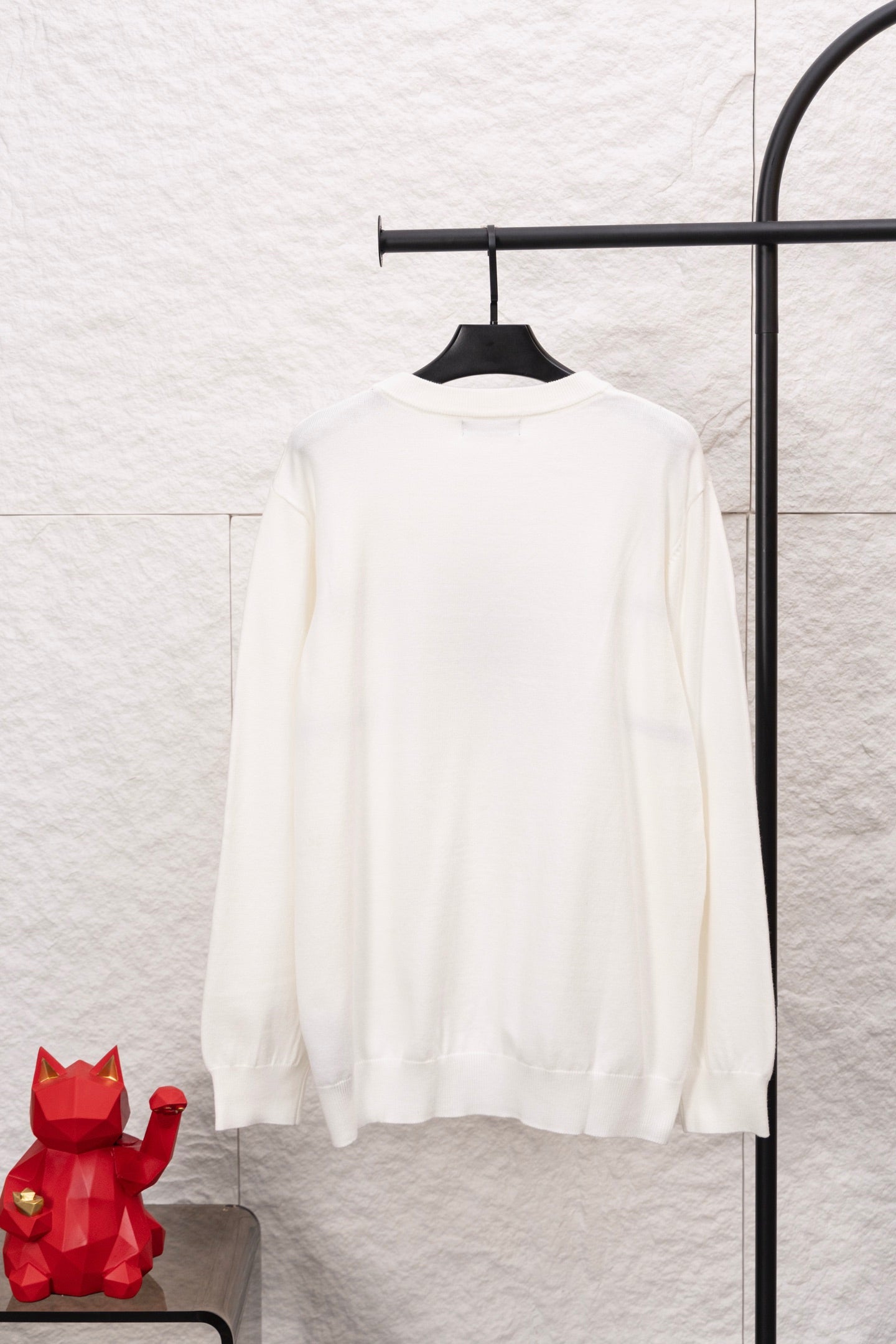 White long-sleeve crewneck sweater on hanger, back view