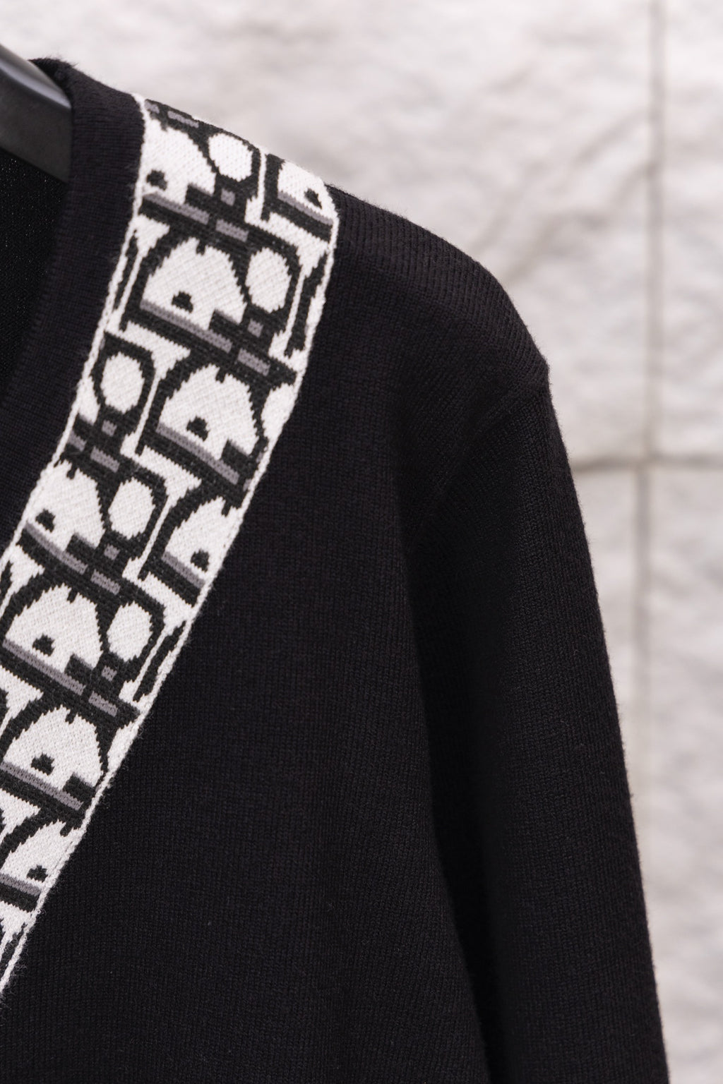 Close-up of black sweater sleeve with white patterned vertical trim