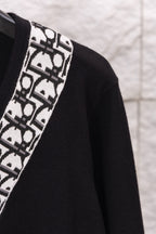 Close-up of black sweater sleeve with white patterned vertical trim
