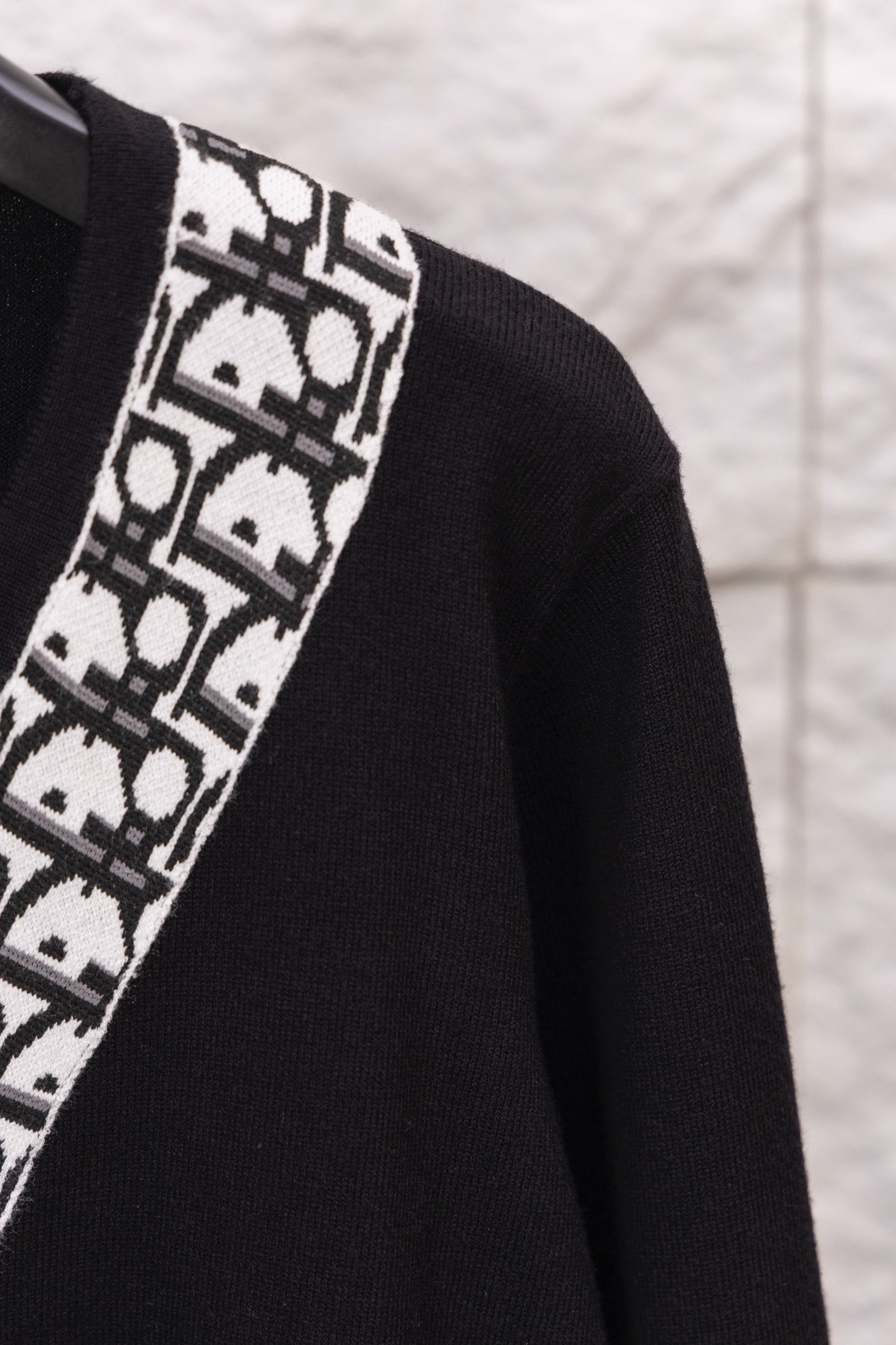 Close-up of black sweater sleeve with white patterned vertical trim