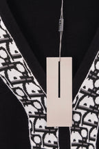 Close-up of black V-neck sweater with white patterned trim and hanging tag