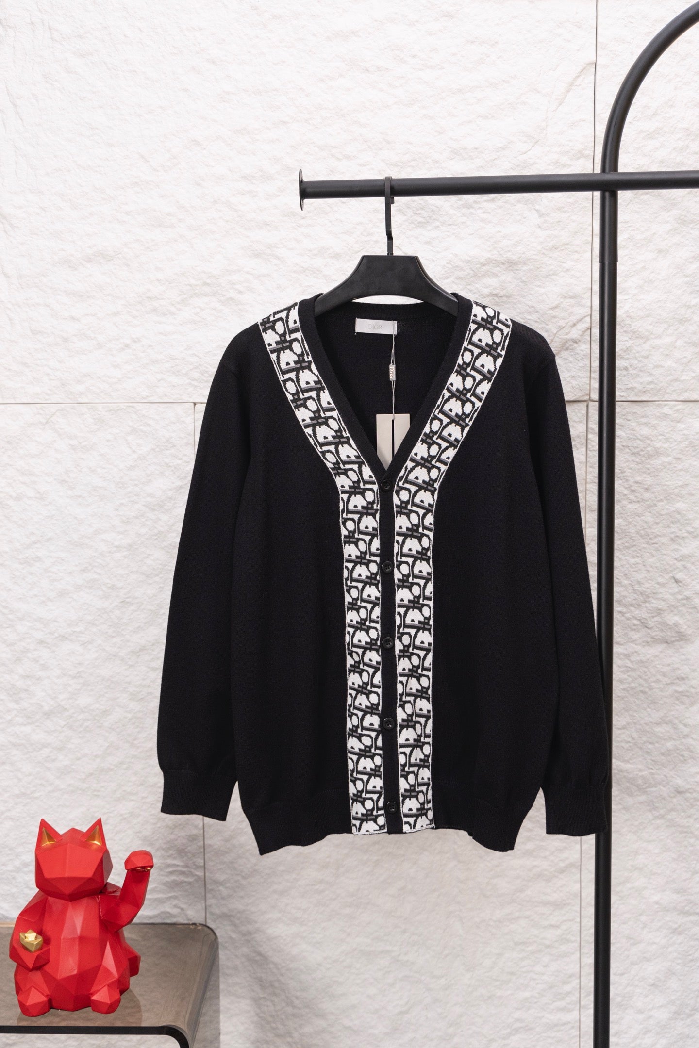 Black long-sleeve V-neck sweater with white patterned front placket and trim