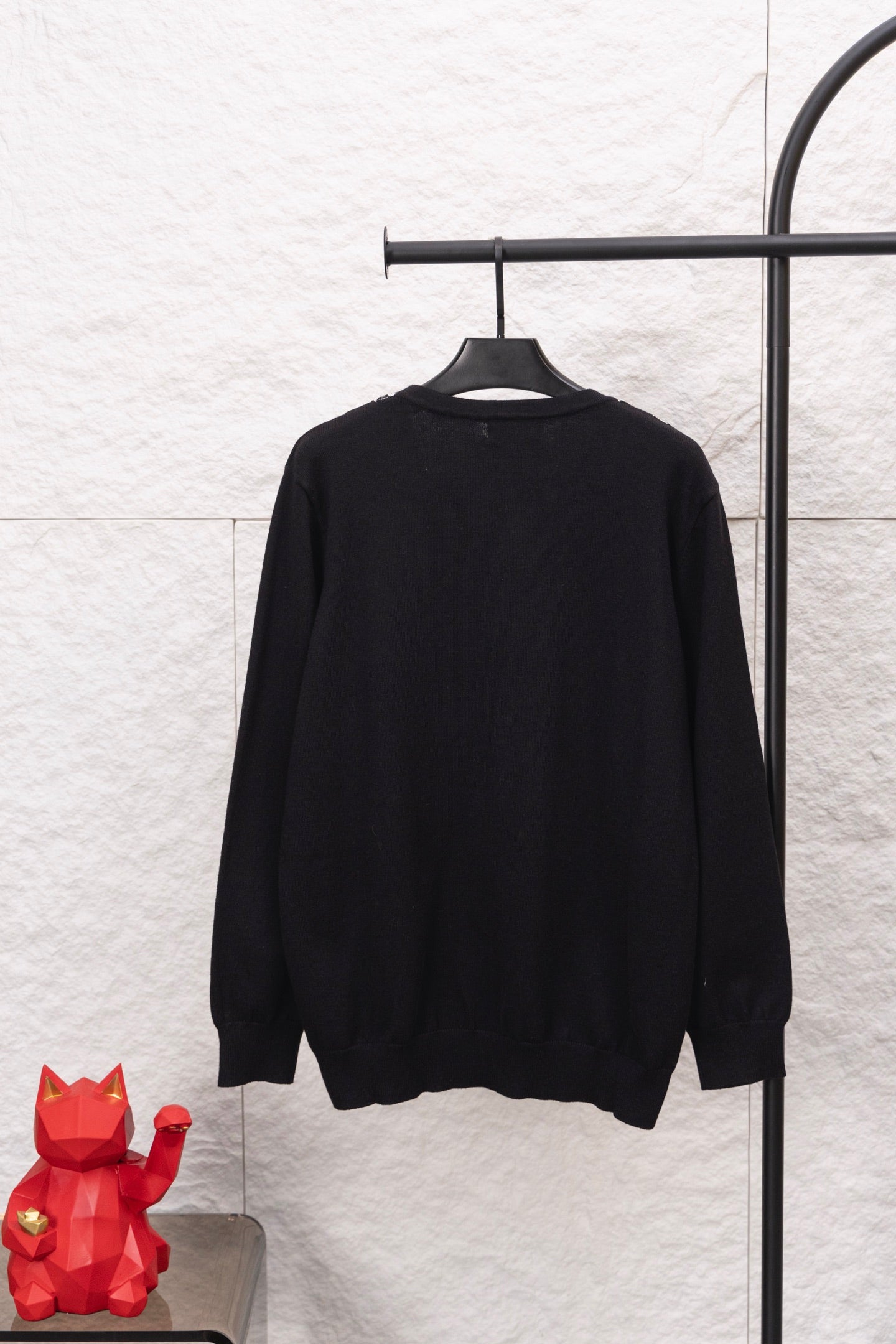 Black long-sleeve sweater with crew neckline on a hanger