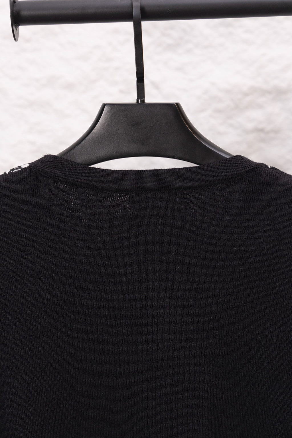 Close-up of black sweater upper back on hanger