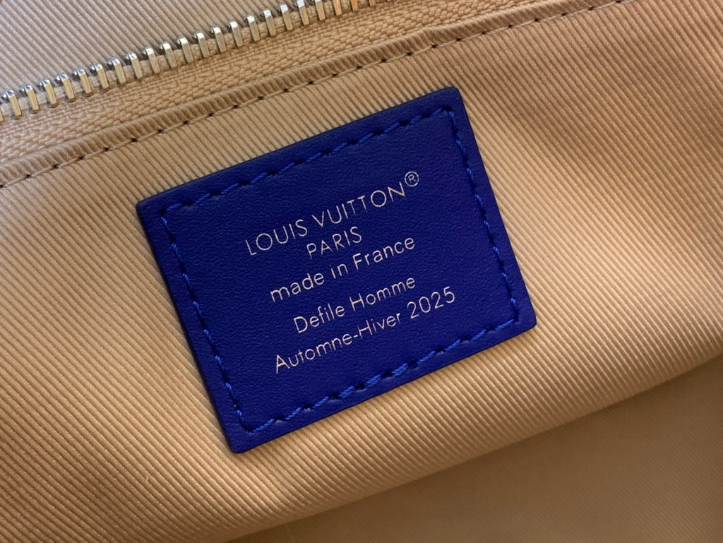 Tan leather tag with blue label reading Louis Vuitton, made in France.