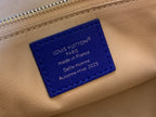 Tan leather tag with blue label reading Louis Vuitton, made in France.
