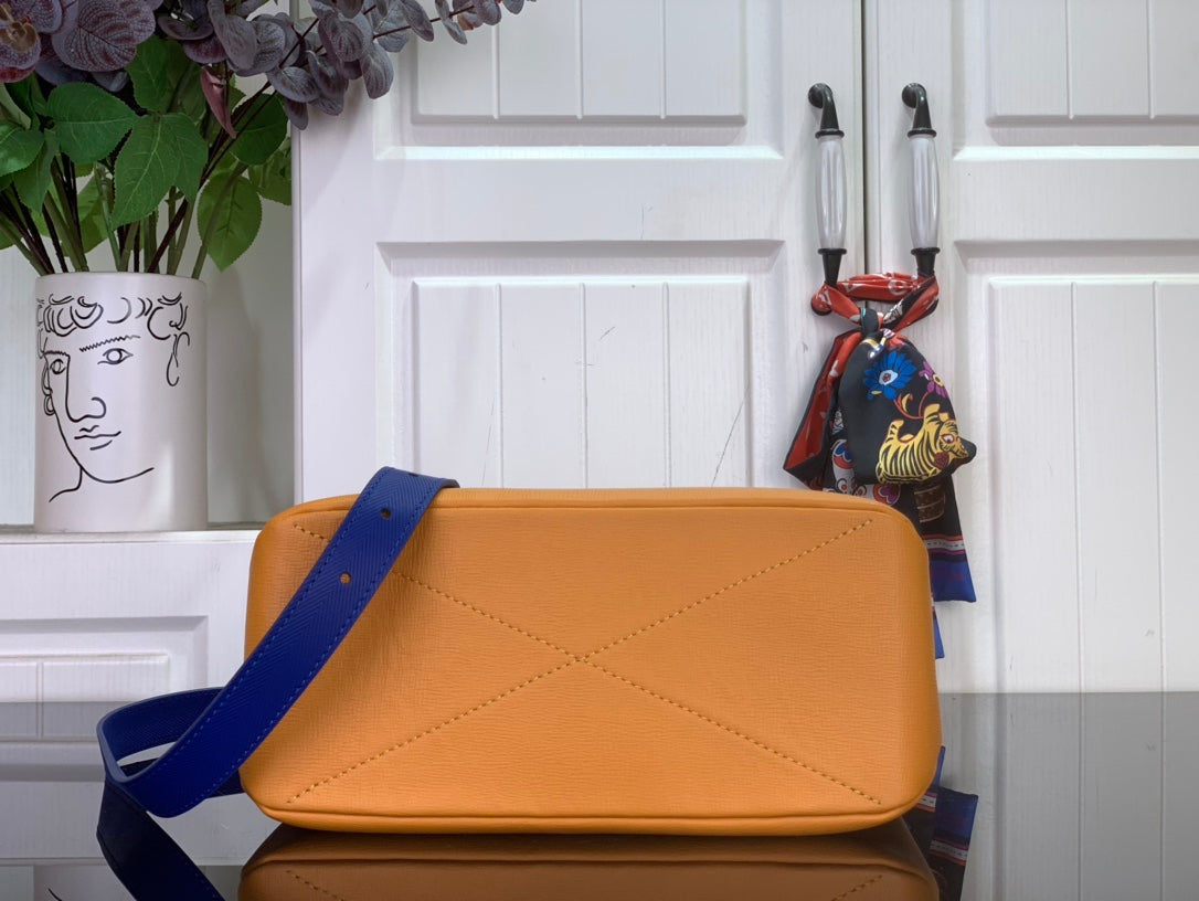 Handbag satchel in orange with blue strap and stitched flap detail.