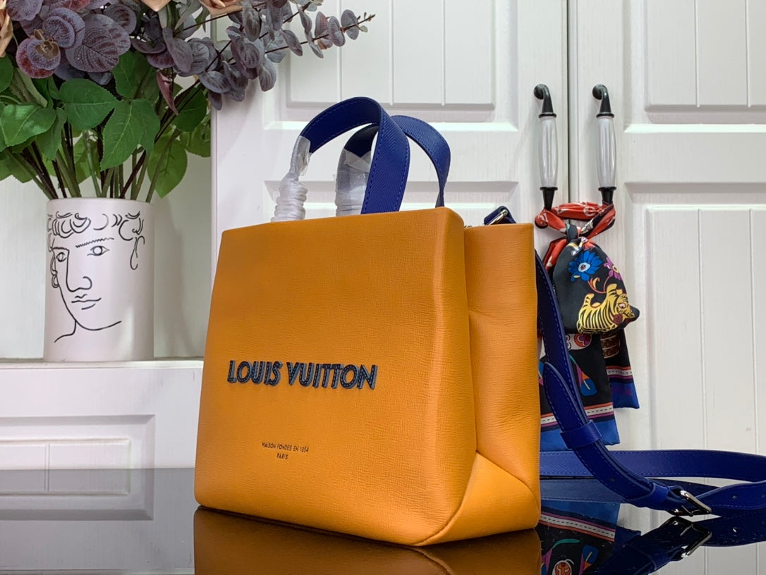 Handbag in orange with blue handles and front logo, angled view.