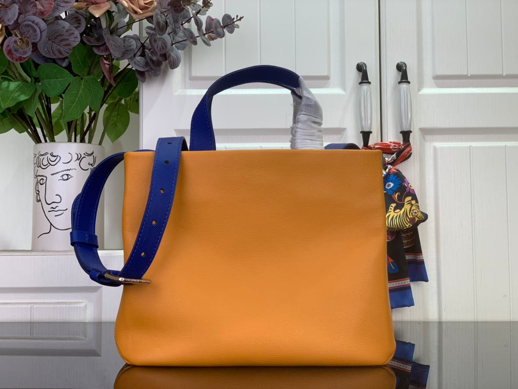 Handbag in orange with blue shoulder strap and top handle, side view.