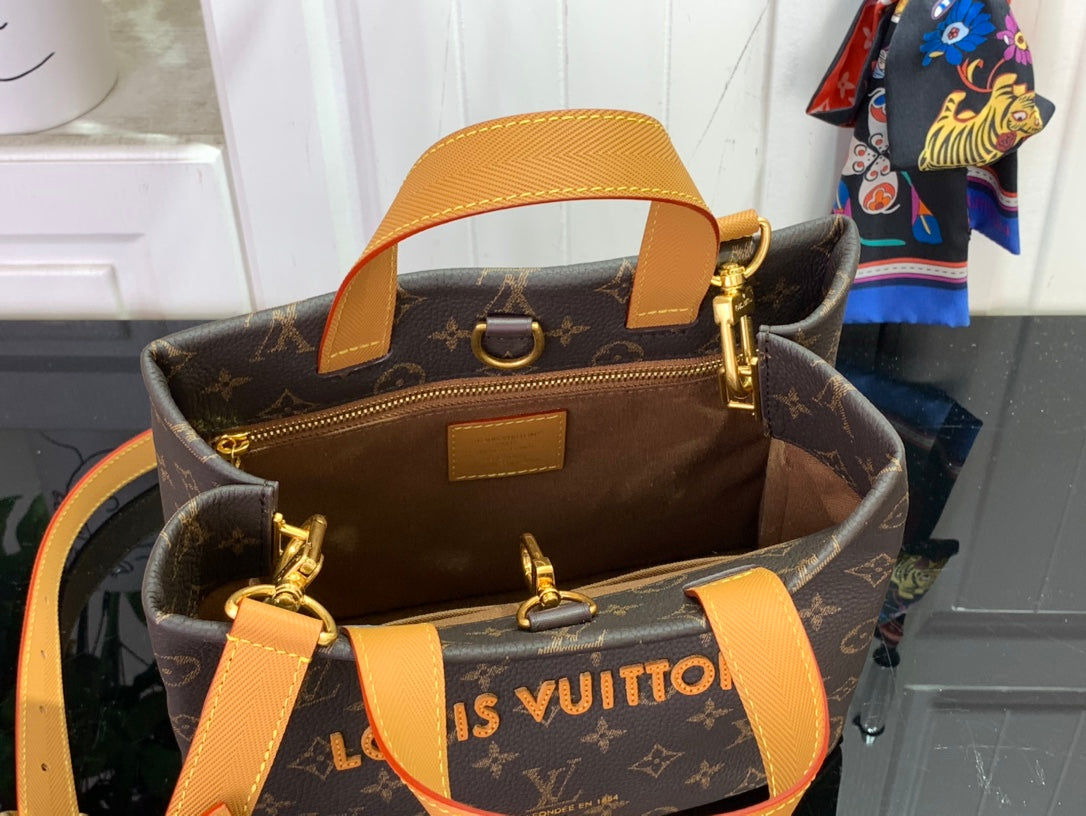 Tote bag with tan leather trim, gold hardware, and monogram canvas exterior.