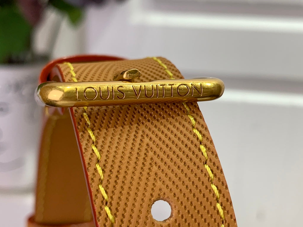 Gold clasp on tan leather strap reading Louis Vuitton.